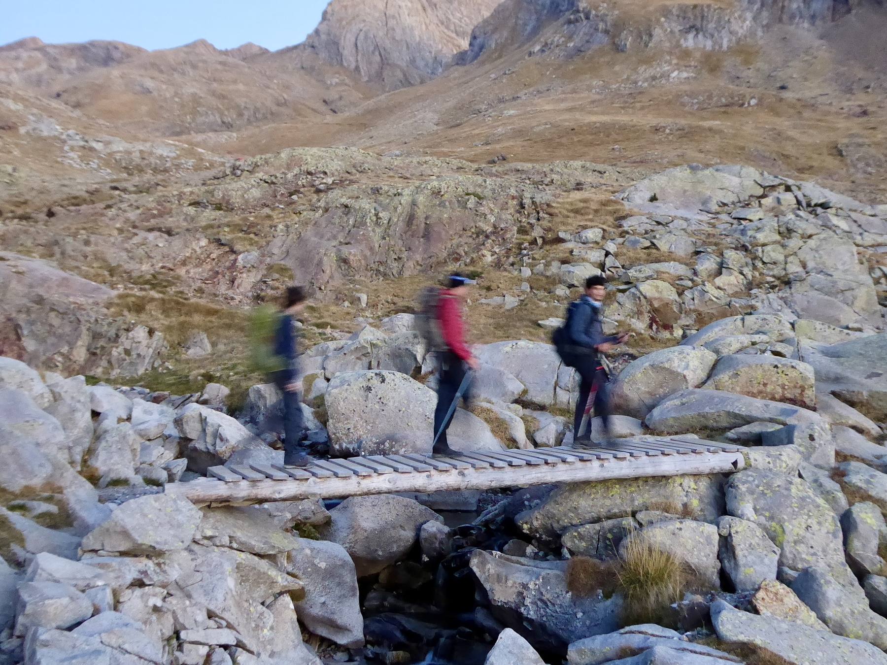 OCMT team crossing a mountain stream on a wooden bridge