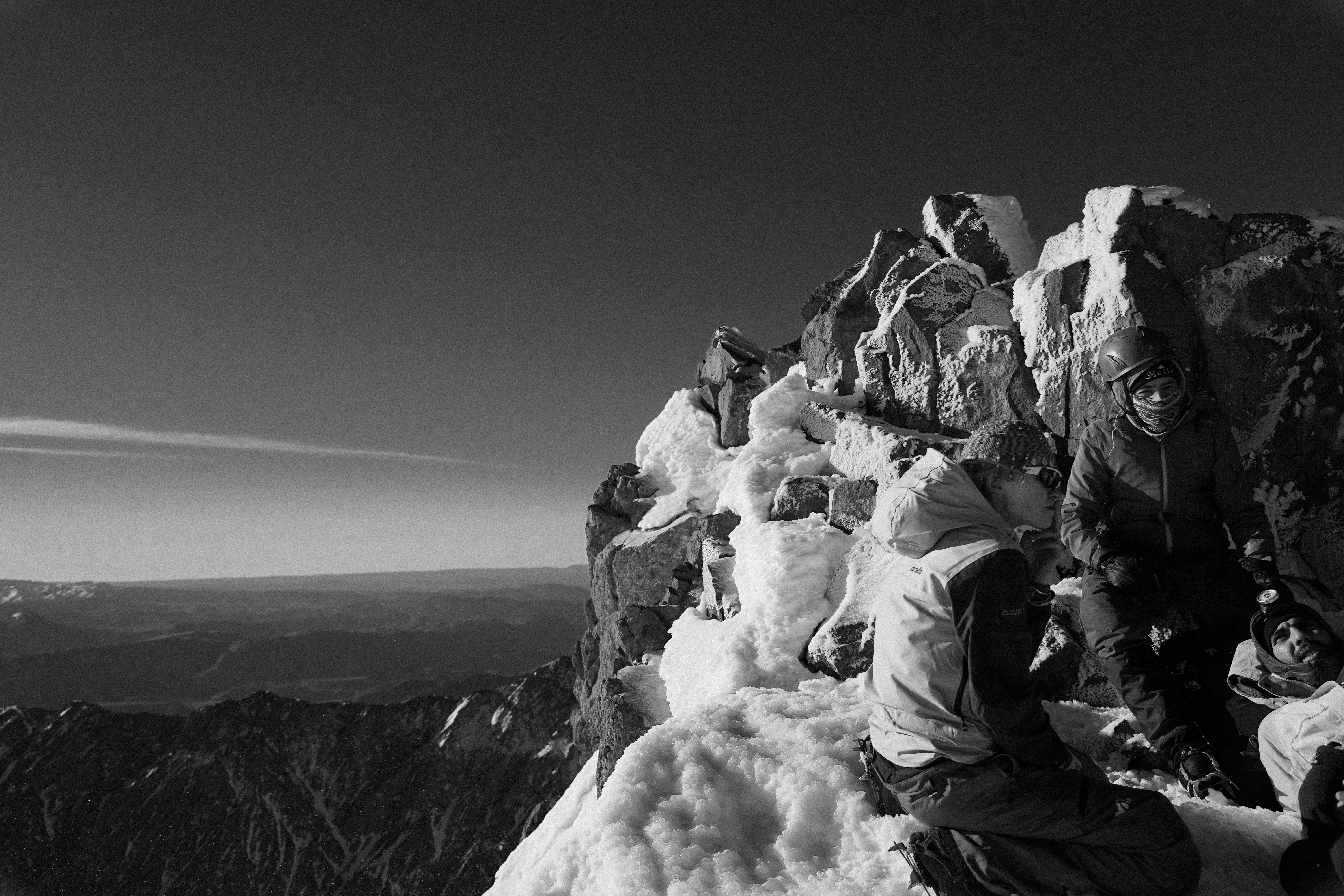 OCMT climbers resting on a snow-covered ridge above the clouds